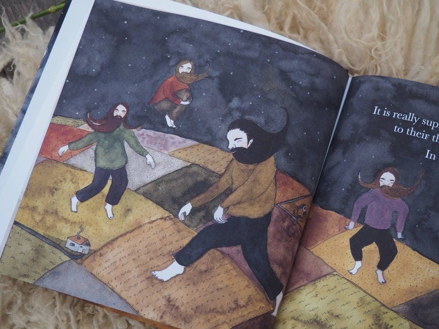 A book lays open to show four bearded giants playing in patches of farmland