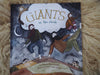 A Giants in the Clouds book sits atop a white sheep fleece.  The book shows a large cloud and four giants dancing on the land under the cloud.