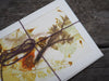 Close up of flower and leaf prints on the front of ecoprinted notecards tied with purple yarn